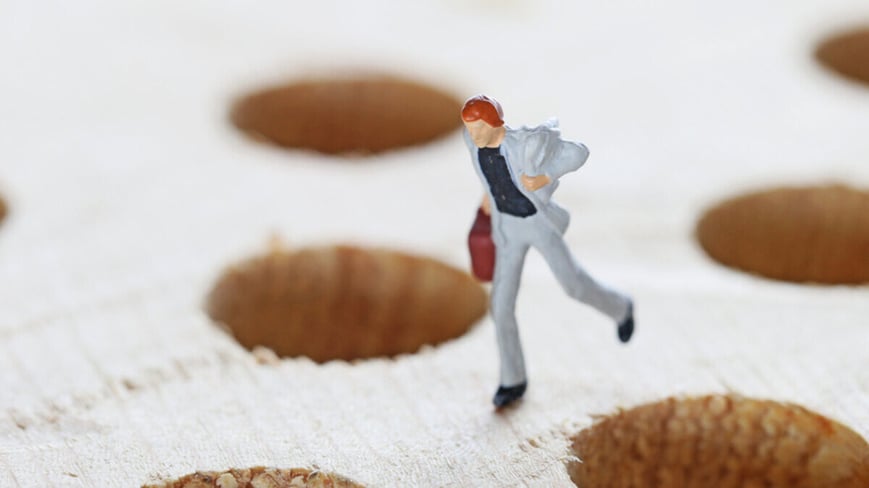 Business owner figurine running through a field of HR pitfalls. 